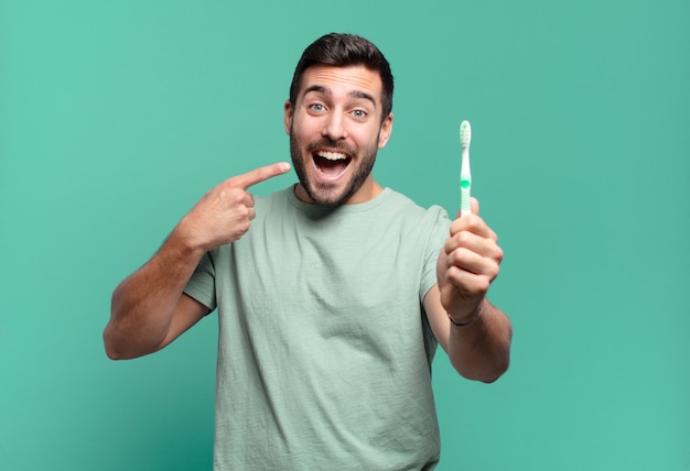 Giovane uomo bello con uno spazzolino da denti.