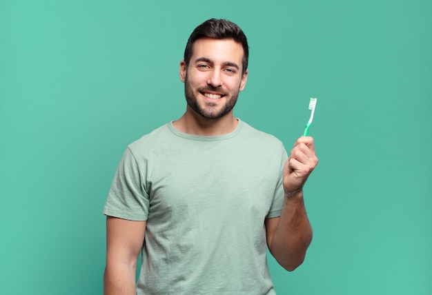 Giovane uomo bello con uno spazzolino da denti.