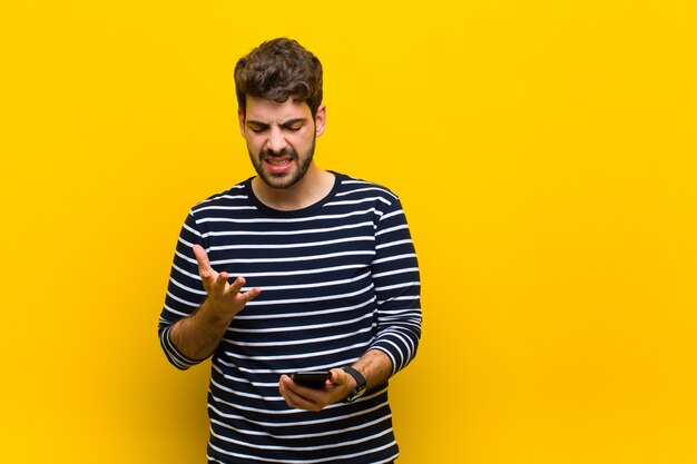 Giovane uomo bello contro la parete arancione