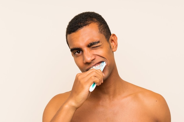 Giovane uomo bello del brunette che pulisce i suoi denti