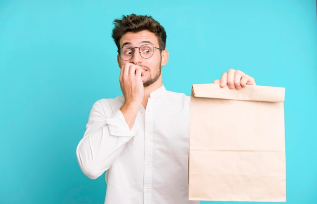 Giovane uomo bello impiegato con un sacchetto di carta per cibo da asporto