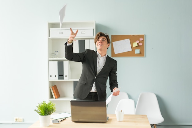 Giovane uomo bello in vestito che si diverte in ufficio