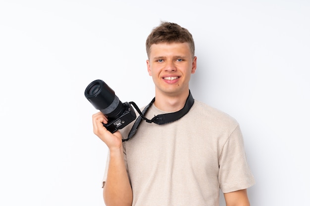 Giovane uomo bello sopra bianco isolato con una macchina fotografica professionale