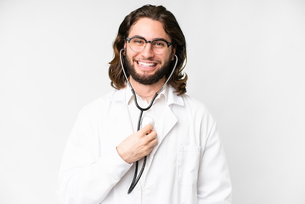 Giovane uomo bello su sfondo bianco isolato che indossa un camice medico e con stetoscopio