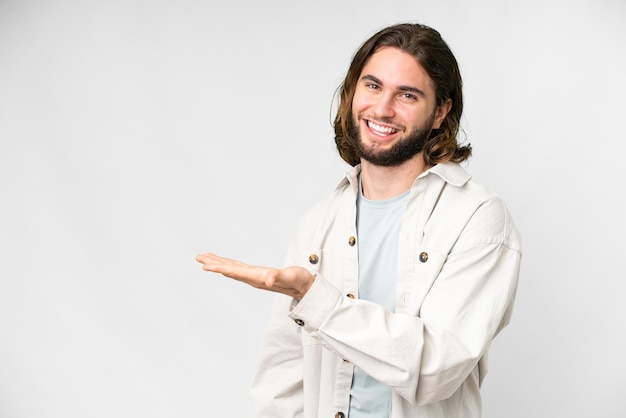 Giovane uomo bello su sfondo bianco isolato che presenta un'idea guardando sorridente verso