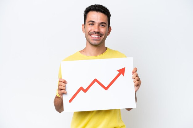 Giovane uomo bello su sfondo bianco isolato con un cartello con un simbolo di freccia di statistiche in crescita con felice espressione