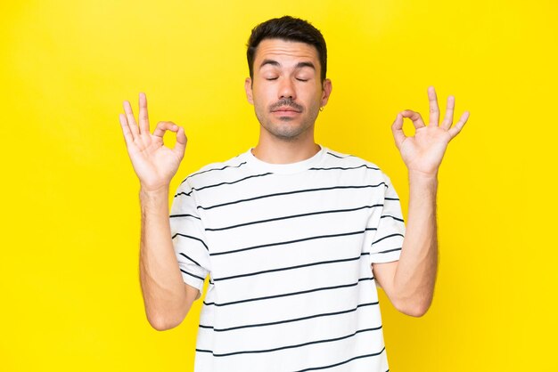 Giovane uomo bello su sfondo giallo isolato in posa zen