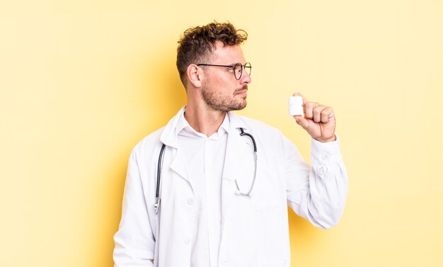 Giovane uomo bello sulla vista di profilo pensando, immaginando o sognando ad occhi aperti. concetto di bottiglia di pillole medico