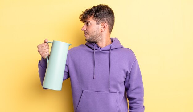 Giovane uomo bello sulla vista di profilo pensando, immaginando o sognando ad occhi aperti. concetto di thermos