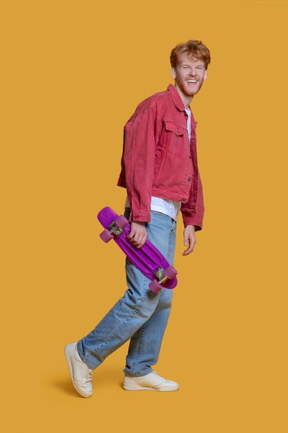 Giovane uomo bello utilizzando lo skateboard