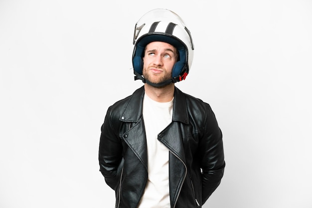 Giovane uomo biondo bello con un casco da motociclista su sfondo bianco isolato e alzando lo sguardo