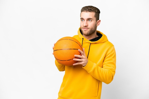 Giovane uomo biondo bello su sfondo bianco isolato giocando a basket