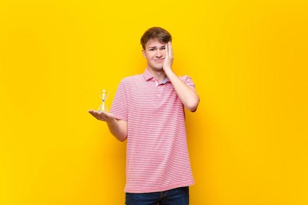 Giovane uomo biondo che tiene un temporizzatore del sandclock