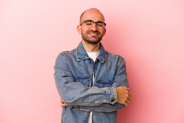 Giovane uomo calvo caucasico isolato su sfondo rosa che si sente sicuro, incrociando le braccia con determinazione.