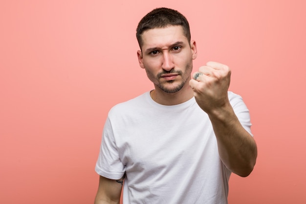 Giovane uomo casual che mostra pugno, espressione facciale aggressiva.