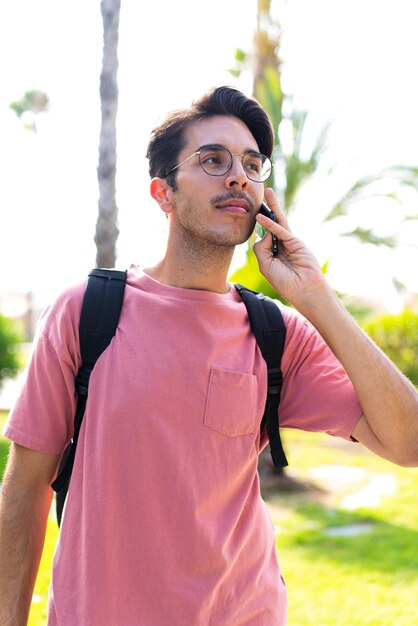 Giovane uomo caucasico all'aperto in un parco utilizzando il telefono cellulare