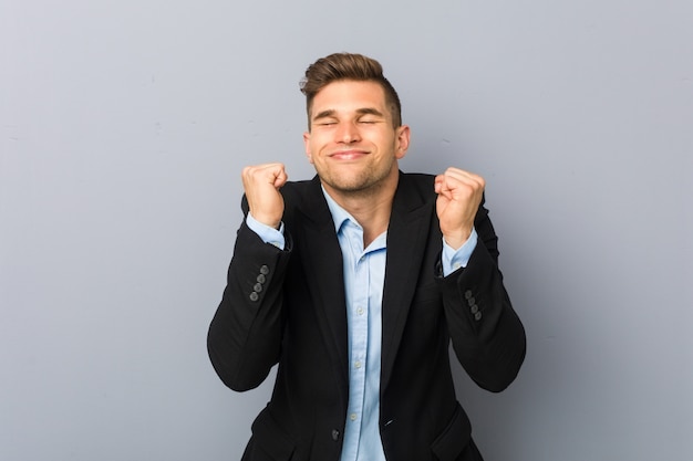 Giovane uomo caucasico bello che alza pugno, sentendosi felice e riuscito. Concetto di vittoria.