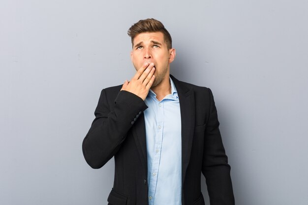 Giovane uomo caucasico bello che sbadiglia mostrando una bocca stanca della copertura di gesto.