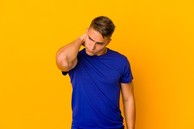 Giovane uomo caucasico bello isolato avendo un dolore al collo a causa dello stress, massaggiandolo e toccandolo con la mano.