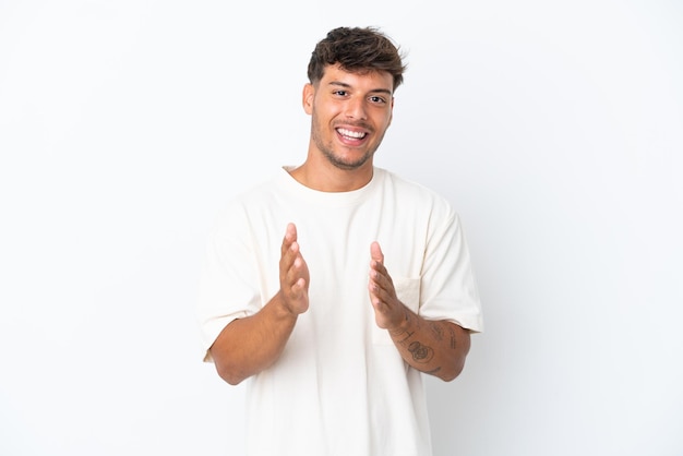 Giovane uomo caucasico bello isolato su sfondo bianco che applaude dopo la presentazione in una conferenza