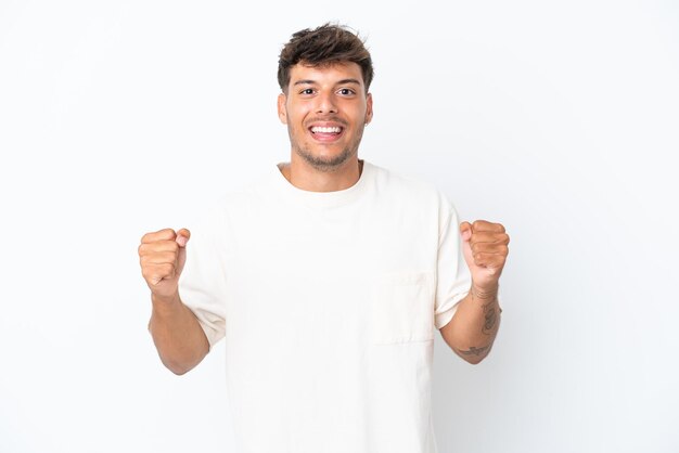 Giovane uomo caucasico bello isolato su sfondo bianco che celebra una vittoria nella posizione del vincitore