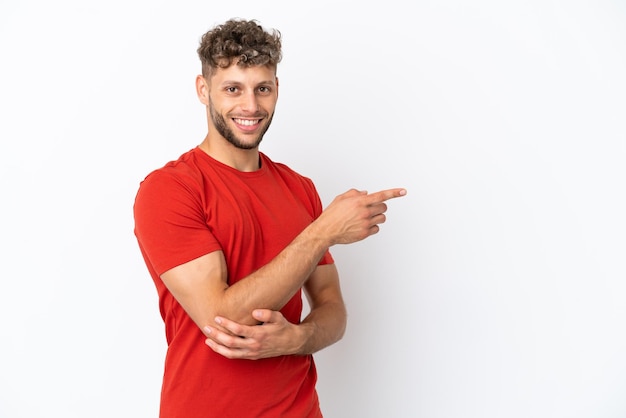 Giovane uomo caucasico bello isolato su sfondo bianco che punta il dito sul lato