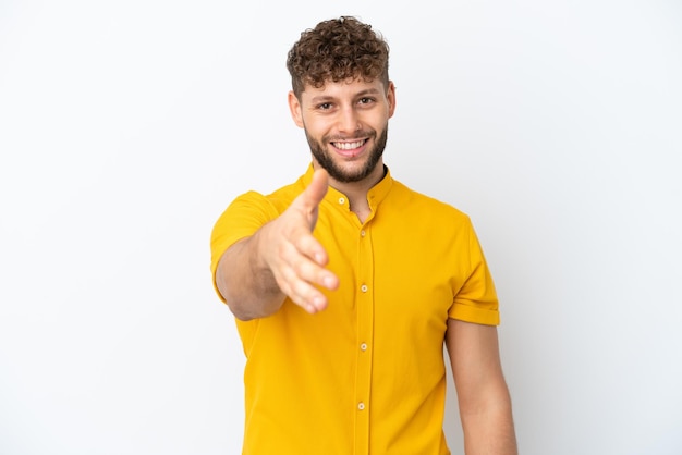 Giovane uomo caucasico bello isolato su sfondo bianco che stringe la mano per chiudere un buon affare