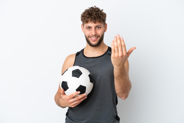 Giovane uomo caucasico bello isolato su sfondo bianco con pallone da calcio e facendo gesto imminente