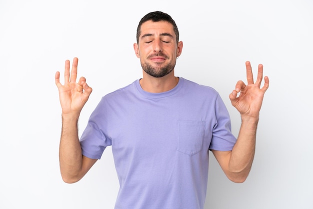 Giovane uomo caucasico bello isolato su sfondo bianco in posa zen