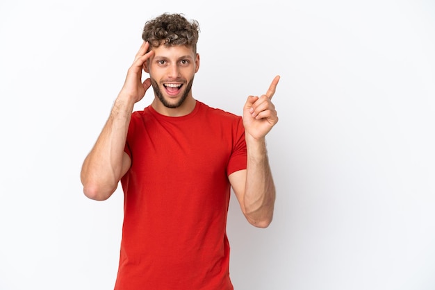 Giovane uomo caucasico bello isolato su sfondo bianco sorpreso e puntando il dito di lato