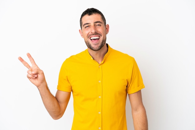 Giovane uomo caucasico bello isolato su sfondo bianco sorridente e mostrando il segno di vittoria