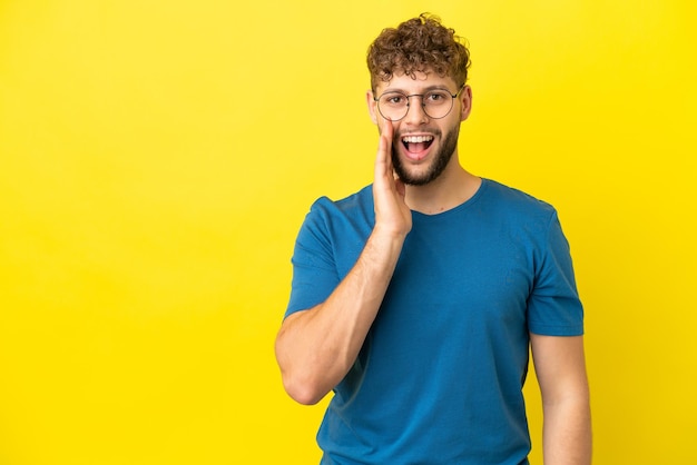 Giovane uomo caucasico bello isolato su sfondo giallo con espressione facciale sorpresa e scioccata