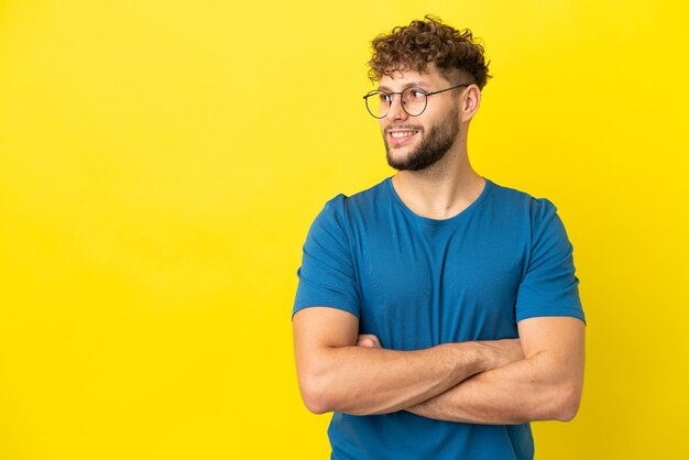 Giovane uomo caucasico bello isolato su sfondo giallo felice e sorridente