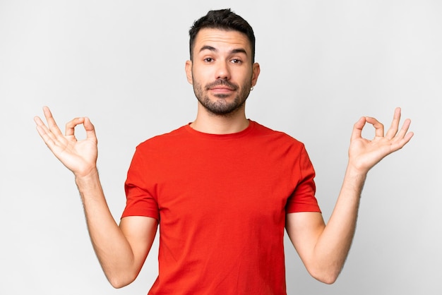 Giovane uomo caucasico bello su sfondo bianco isolato in posa zen