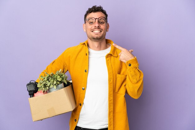 Giovane uomo caucasico che fa una mossa mentre si prende una scatola piena di cose isolate