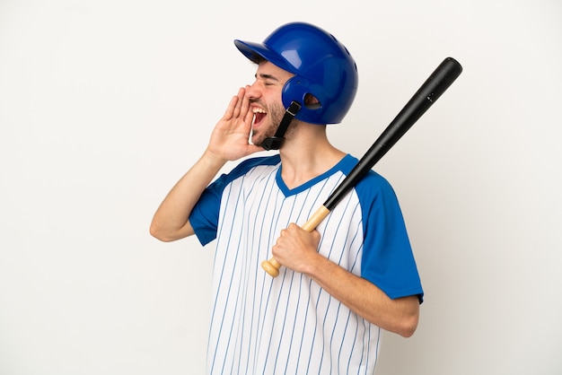 Giovane uomo caucasico che gioca a baseball isolato su sfondo bianco gridando con la bocca spalancata di lato