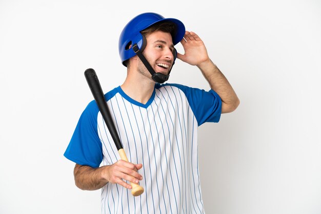 Giovane uomo caucasico che gioca a baseball isolato su sfondo bianco sorridendo molto