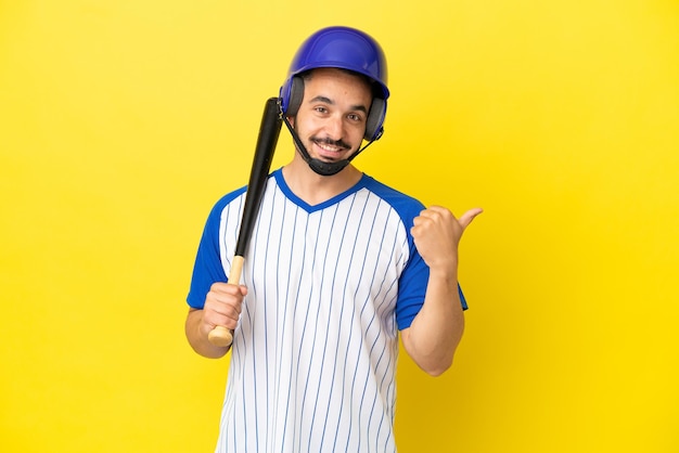 Giovane uomo caucasico che gioca a baseball isolato su sfondo giallo rivolto verso il lato per presentare un prodotto