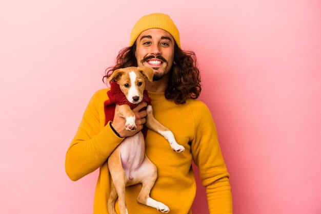 Giovane uomo caucasico che tiene il suo cucciolo isolato su sfondo rosa