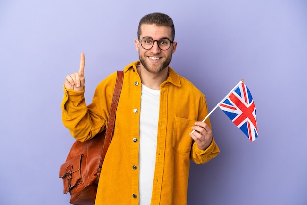 Giovane uomo caucasico che tiene una bandiera del Regno Unito isolata sulla porpora che indica una grande idea