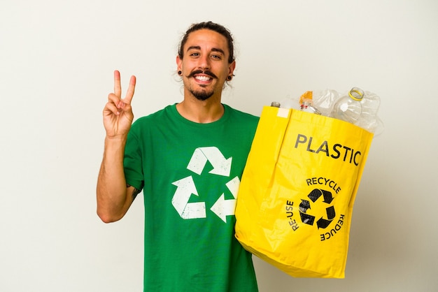 Giovane uomo caucasico con capelli lunghi che riciclano plastica isolata su sfondo bianco che mostra il numero due con le dita.