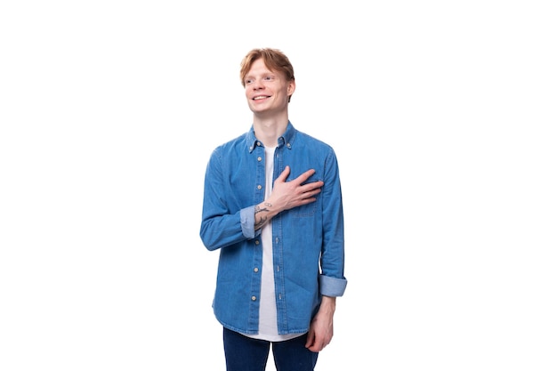 Giovane uomo caucasico con i capelli rossi vestito con una camicia blu su uno sfondo bianco con spazio di copia