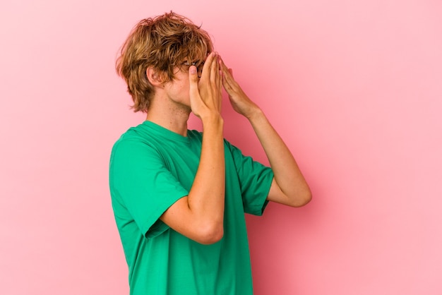 Giovane uomo caucasico con make up isolato su sfondo rosa impaurito che copre gli occhi con le mani.