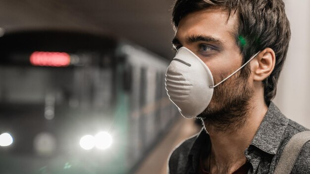 Giovane uomo caucasico con maschera di protezione contro il virus alla stazione pubblica della metropolitana