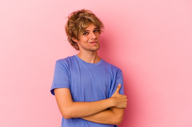 Giovane uomo caucasico con trucco isolato su sfondo rosa infelice guardando a porte chiuse con espressione sarcastica.