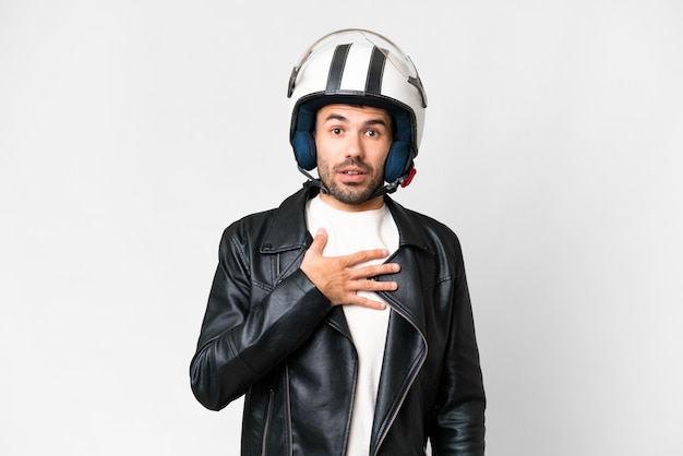 Giovane uomo caucasico con un casco da motociclista su sfondo bianco isolato sorpreso e scioccato guardando a destra