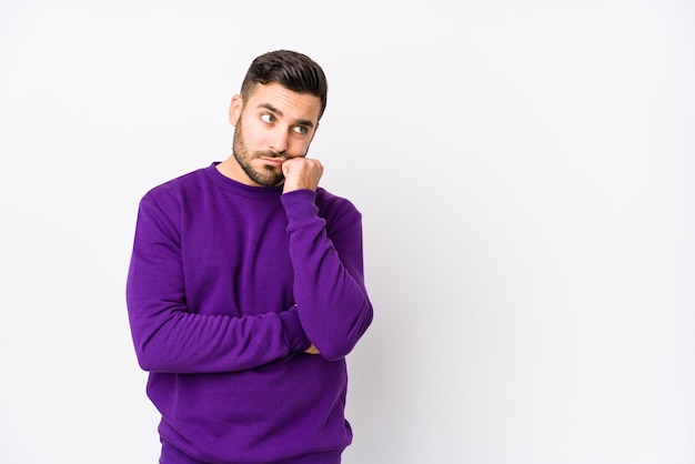 Giovane uomo caucasico contro un muro bianco isolato che si sente triste e pensieroso, guardando lo spazio della copia.