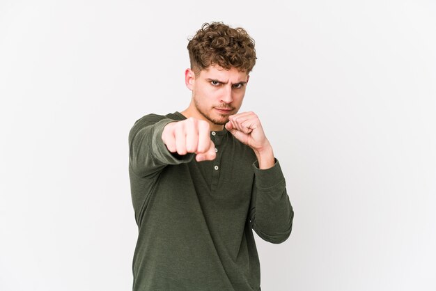 Giovane uomo caucasico dei capelli ricci biondi isolato lanciando un pugno, rabbia, combattimenti a causa di una discussione, boxe.