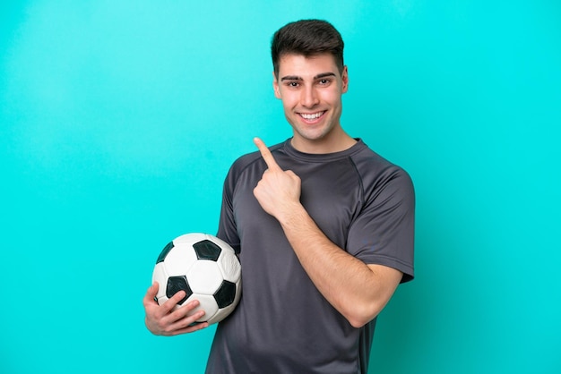 Giovane uomo caucasico del giocatore di football isolato su sfondo blu che indica il lato per presentare un prodotto