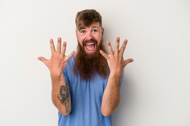 Giovane uomo caucasico dello zenzero con la barba lunga isolata su fondo bianco che mostra il numero dieci con le mani.